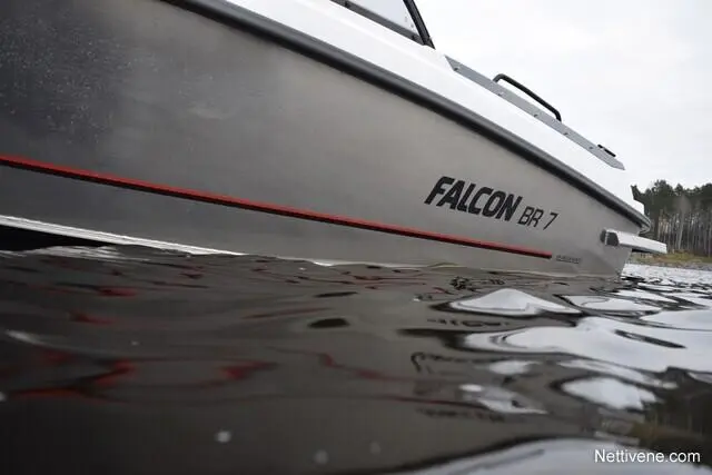 A close-up of the FALCON BR 7 boat, partially submerged in water with a forest background. Visible reflections on the water surface.